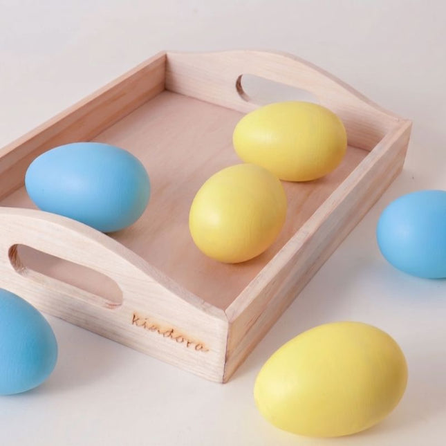 Colorful eggs on a wooden tray with 'Kinder' branding on a light background